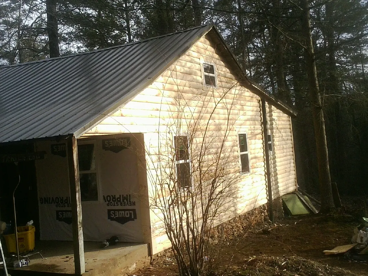 Log siding gable end under a dark metal roof edge in Crofton