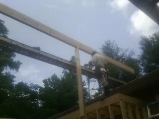 Carpenter setting a ridge beam over a new addition frame — Ice Dam Removal by Roofing Brothers in Crofton