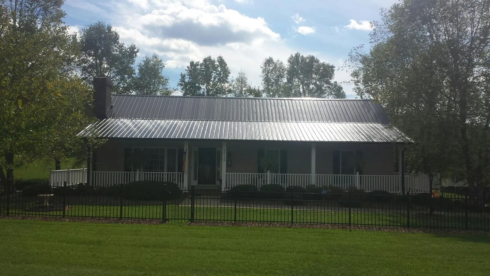 Gray metal roof on a brick ranch with a full width front porch — Gutter Guard Installation work by our crew in Crofton
