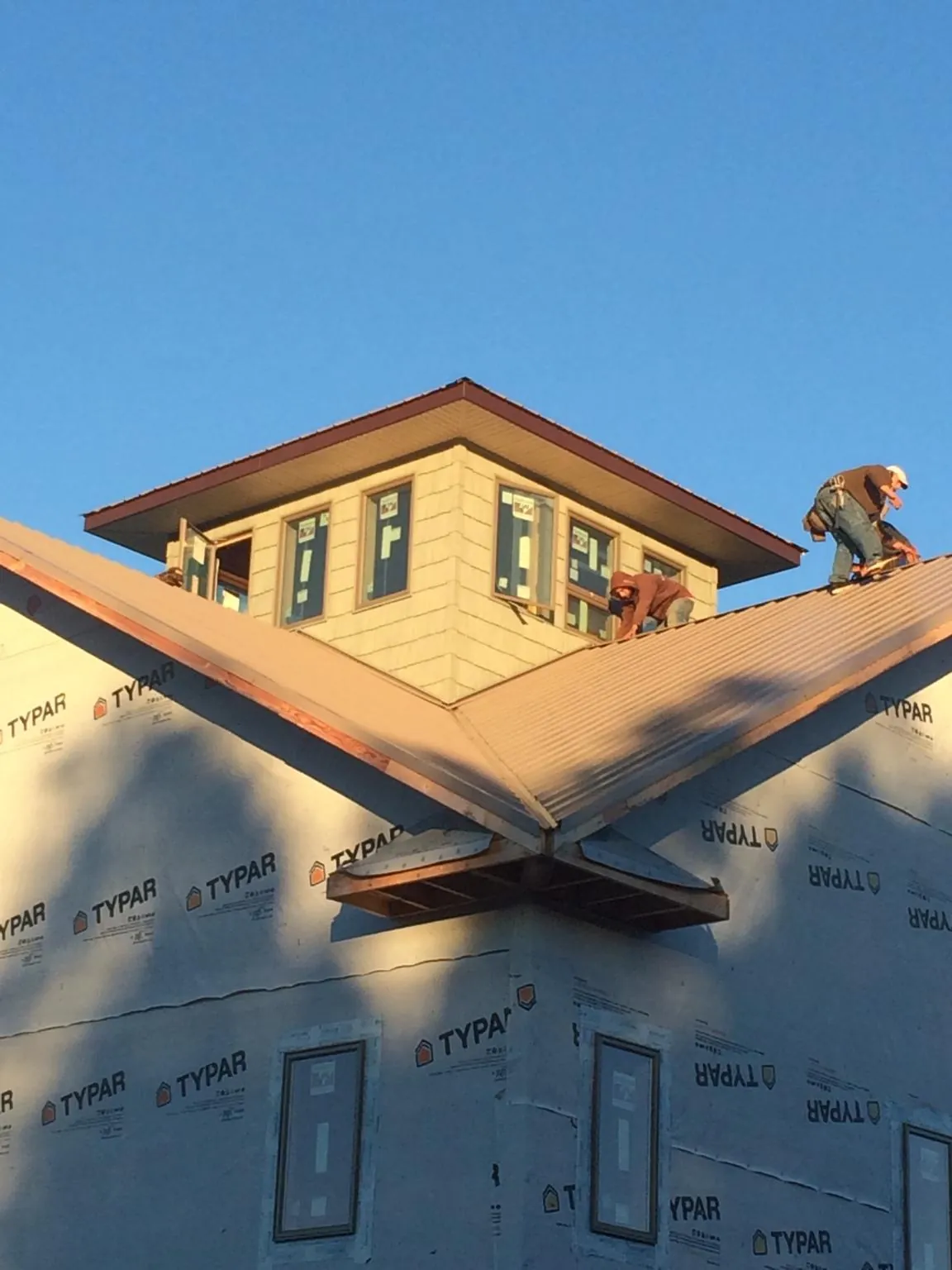 Roofers working around a rooftop cupola on a new metal roof at sunset — Roof Waterproofing in Crofton by Roofing Brothers